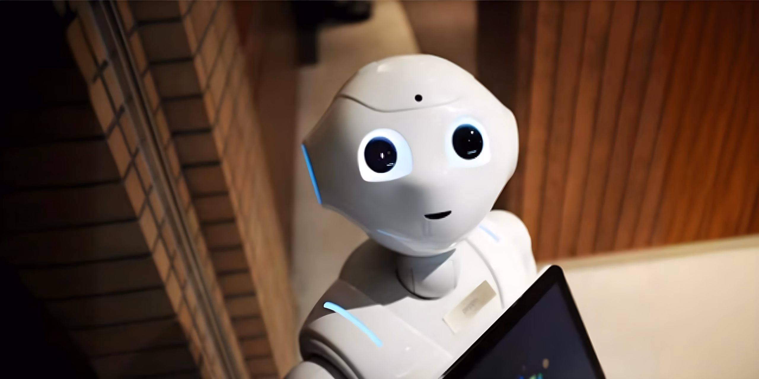 freepik_edit Humanoider Roboter mit großen, leuchtenden Augen blickt freundlich in die Kamera, moderne Umgebung im Hintergrund.