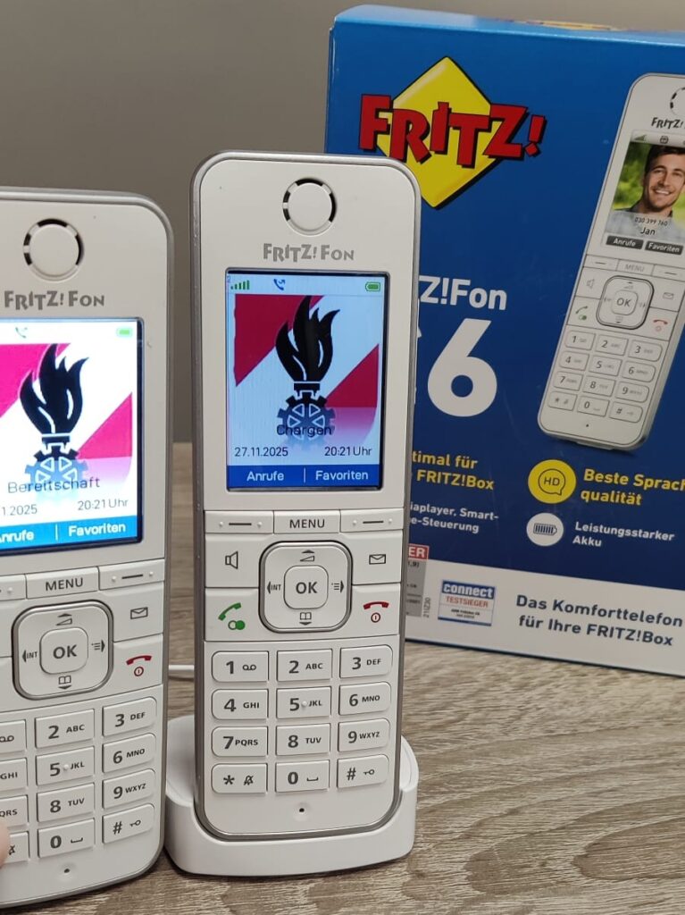 DECT Feuerwehr Eichgraben: Zwei FRITZ!Fon C6 Schnurlostelefone mit Feuerwehr-Wappen auf dem Farbdisplay neben der Originalverpackung – neue Einsatzkommunikation von SKAWINSKI GmbH