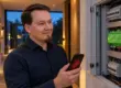 Robert Skawinski mit Smartphone ohne Verbindung vor dem geöffneten Verteilerschrank mit Loxone Miniserver – Remote Connect ab 1. Dezember 2026 nur mit aktueller Software